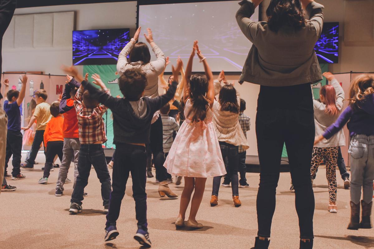 Children dancing in open room with instructor at front