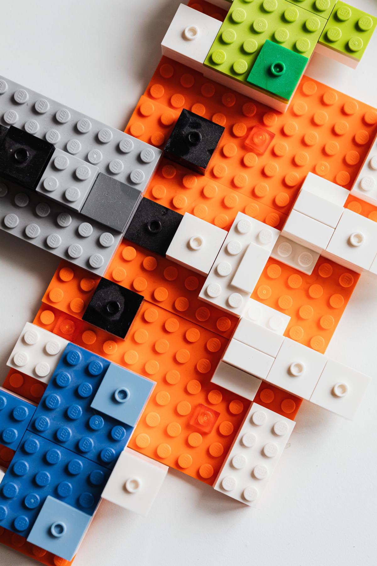 Abstract Lego arrangement with orange, white, green, grey, and blue blocks